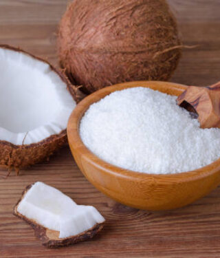 coconut flakes in a bowl on brown wooden background